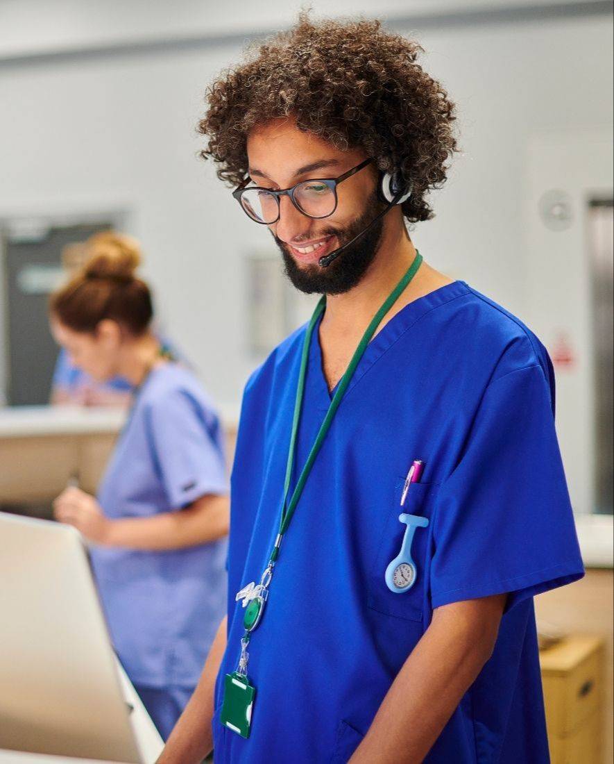 Happy male nurse standing and typing