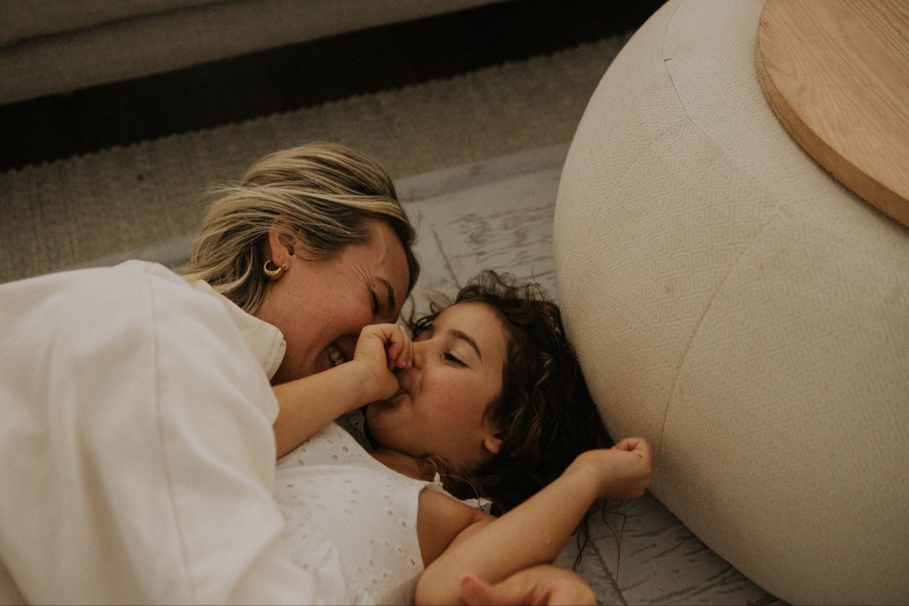 A woman lying on the floor smiling and hugging her young daughter