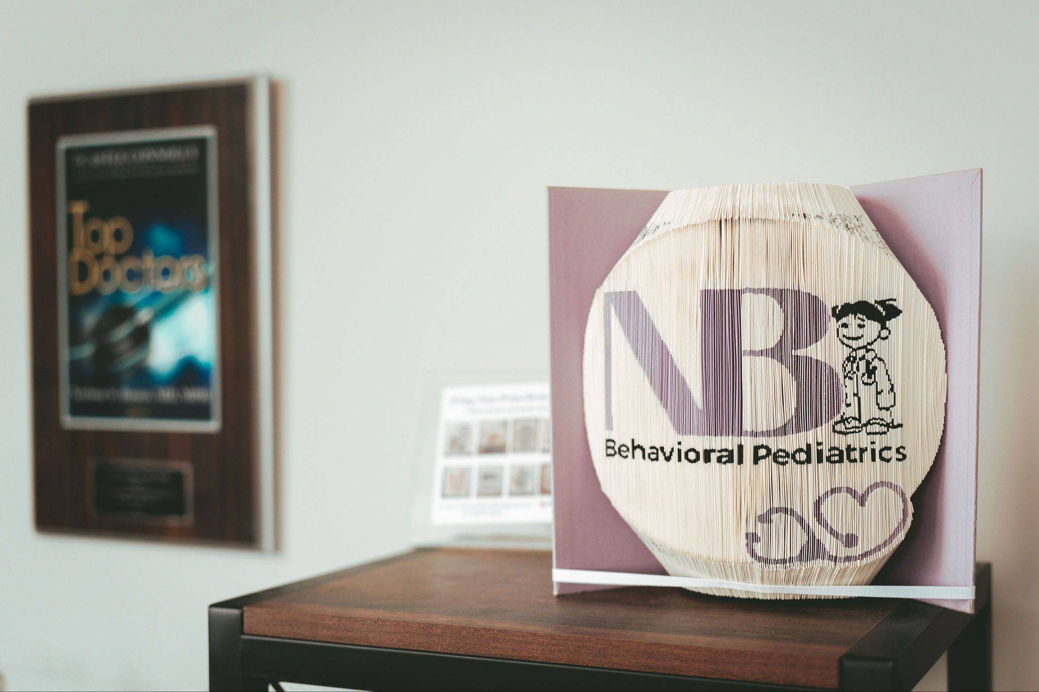 An open book standing upright is on a wooden stand. You can see the NB Behavioral Pediatrics logo on the edges of the pages.