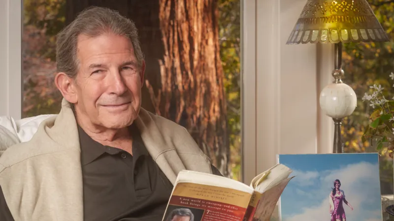 Gary Zukav sits by a window holding an open copy of The Seat of the Soul