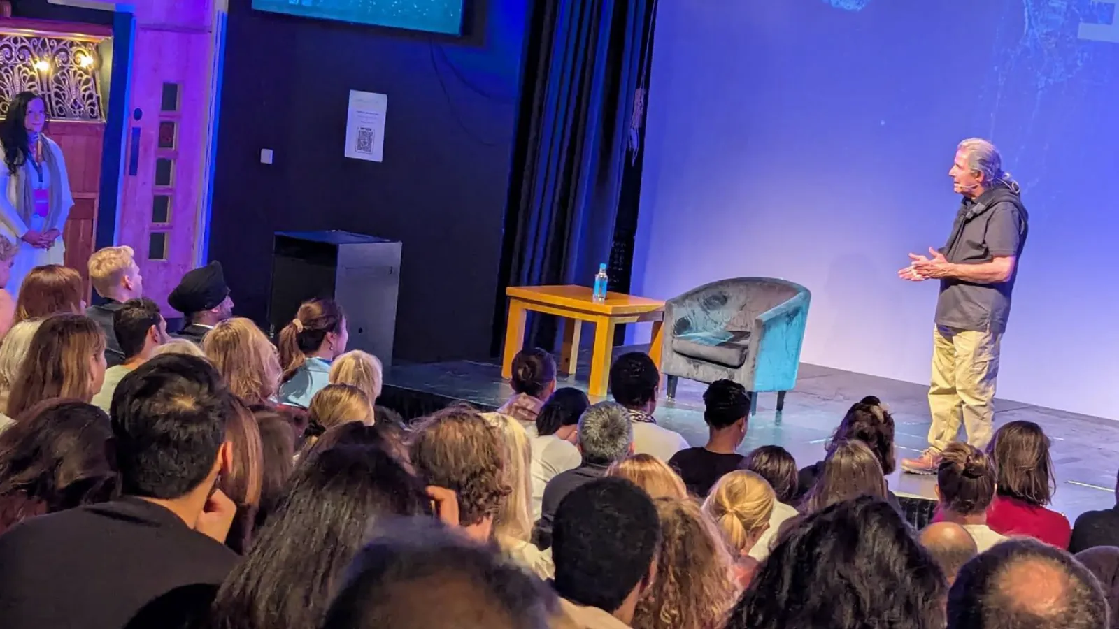 Gary Zukav speaks on stage to a full audience at a live event