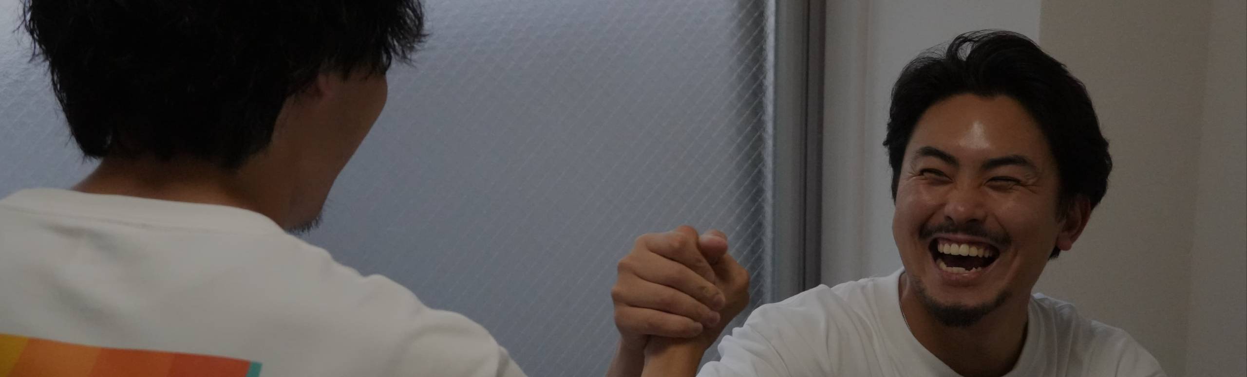 腕相撲をしながら笑い合う株式会社太陽のスタッフ