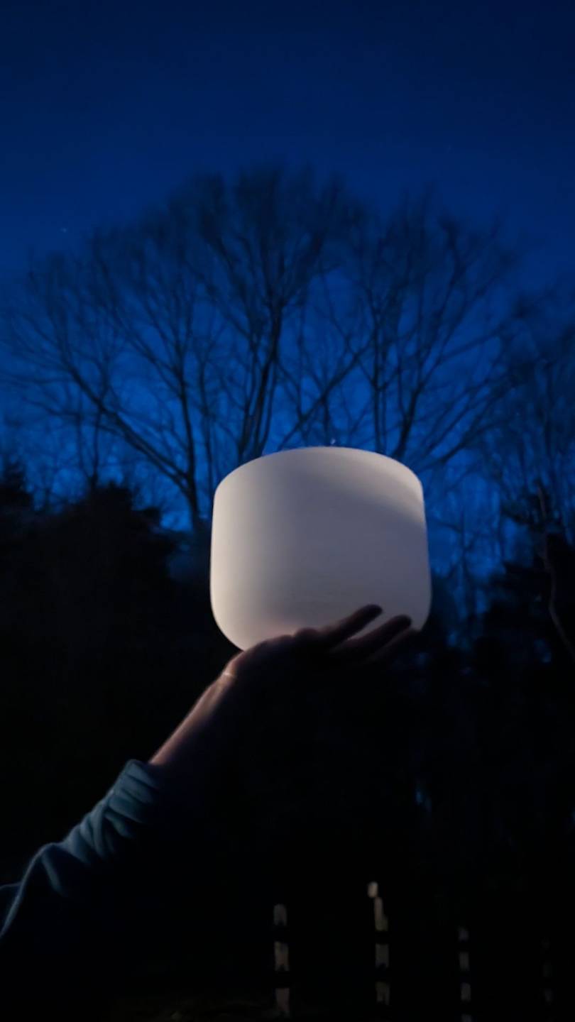 A person holding up a drum against a star-filled sky at night
