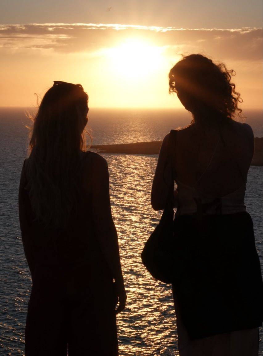 Zwei Teilnehmende beobachten den Sonnenuntergang am Meer