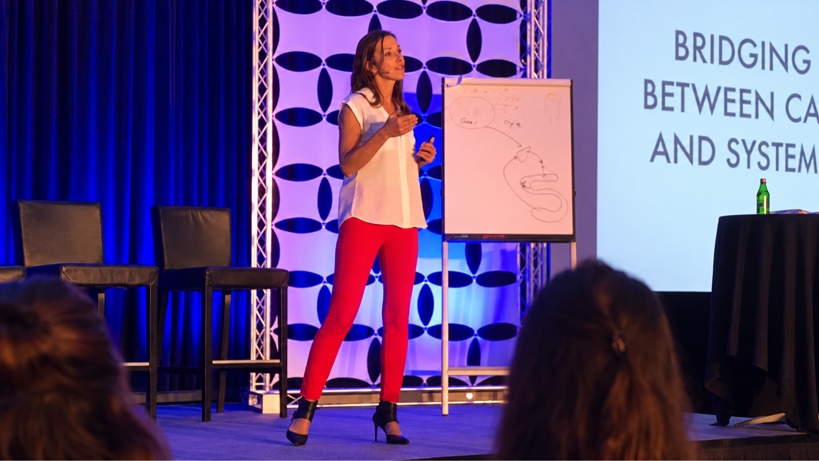 Dr. Caitlin Czezowski speaking on stage before a live audience