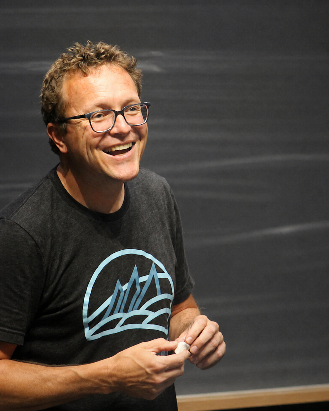 Coach Jay Johnson smiling in front of a chalkboard