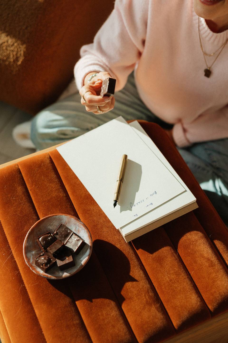 Dark chocolate squares in a small dish beside an open journal