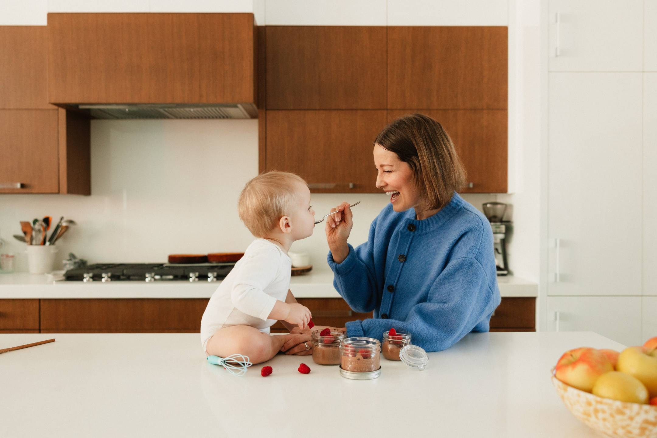Arianne in her kitchen sharing a spoonful of chocolate pudding with her baby
