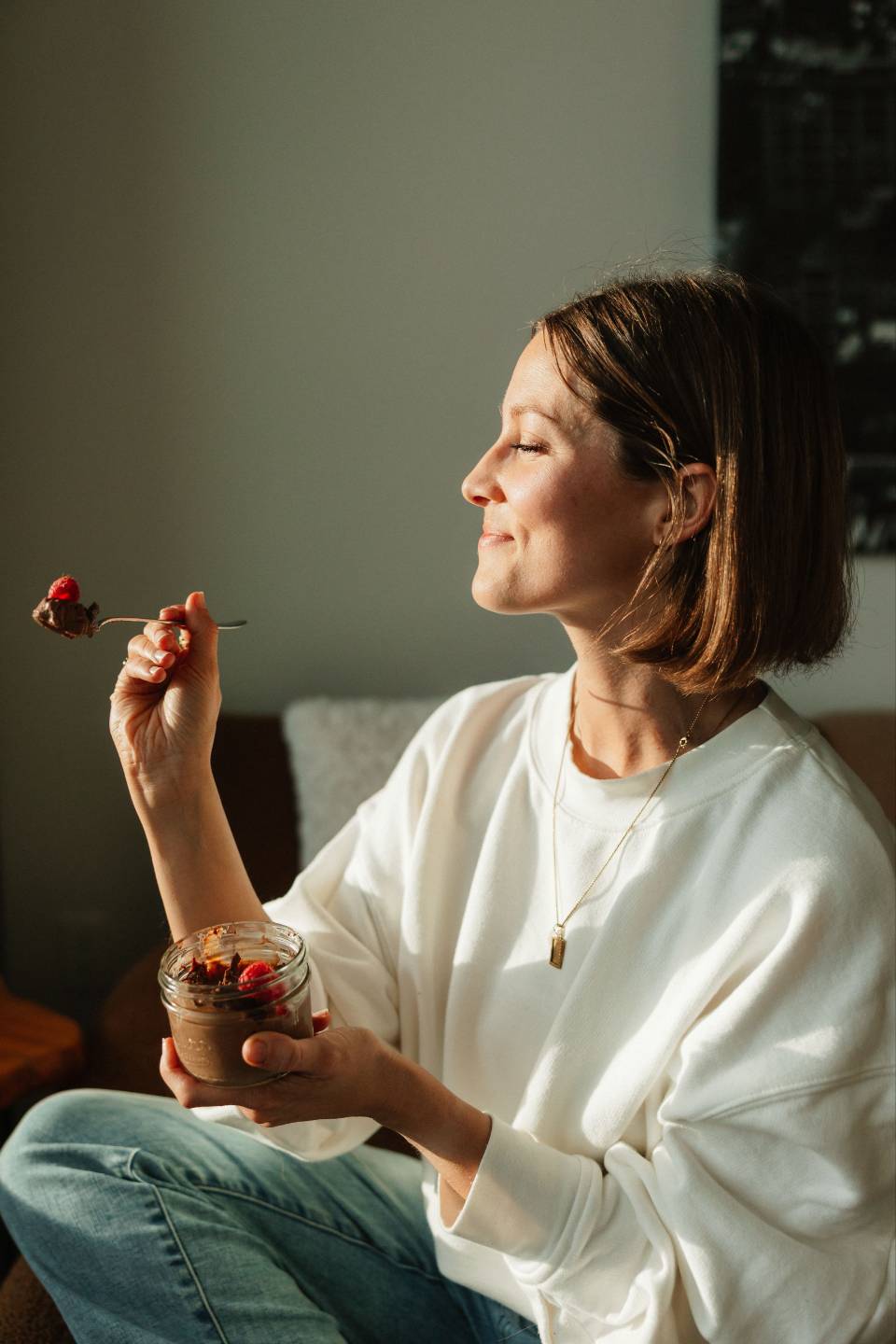 Arianne sitting in afternoon light eating a chocolate pudding with fresh berries