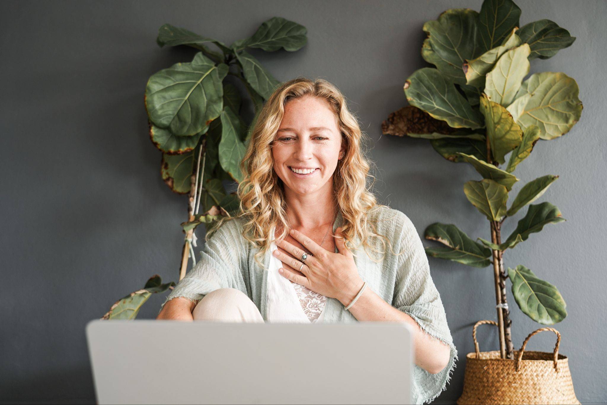 Maeve Downey smiling with her hand on her heart in front of a laptop, ready to connect online
