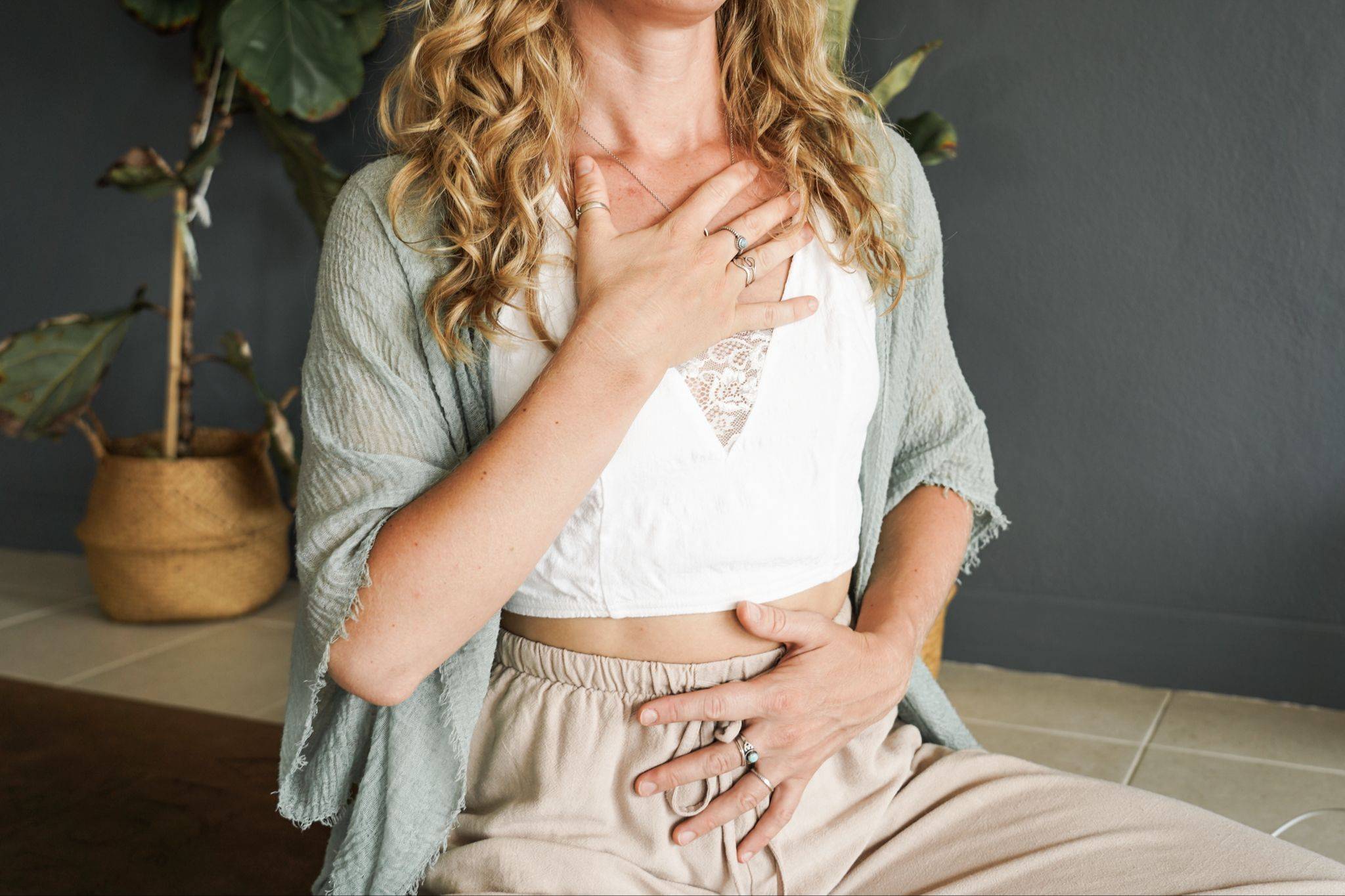 Woman with one hand on her chest, settling her nervous system with slow breathing
