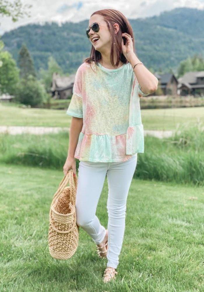 Megan Vanya standing in a green field holding a large purse.