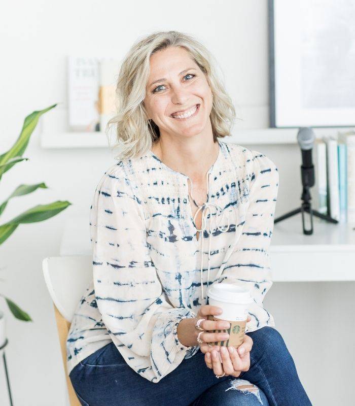 Ciara Stockeland sitting behind a microphone at a desk holding a coffee cup.