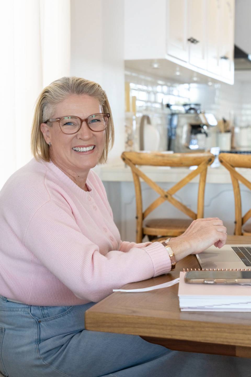 Erin Davis smiling at her desk with a laptop and notebook at the Dudley shoot