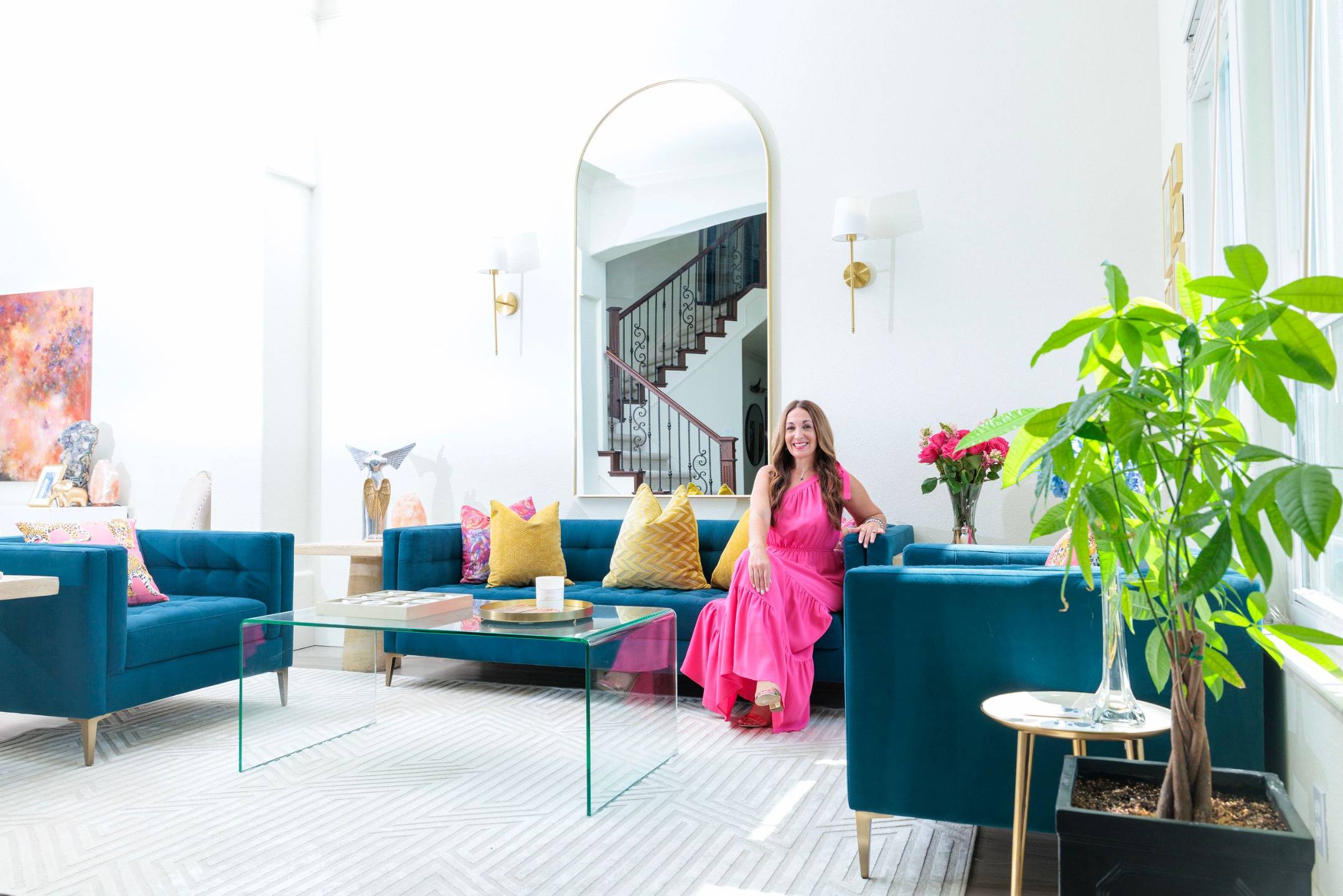 Gina Nicole sitting on a blue velvet sofa in her bright living room
