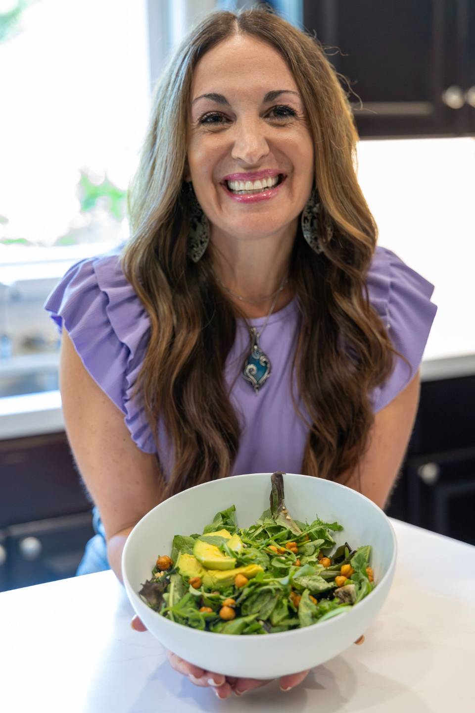Gina Nicole smiling, holding a bowl of fresh salad