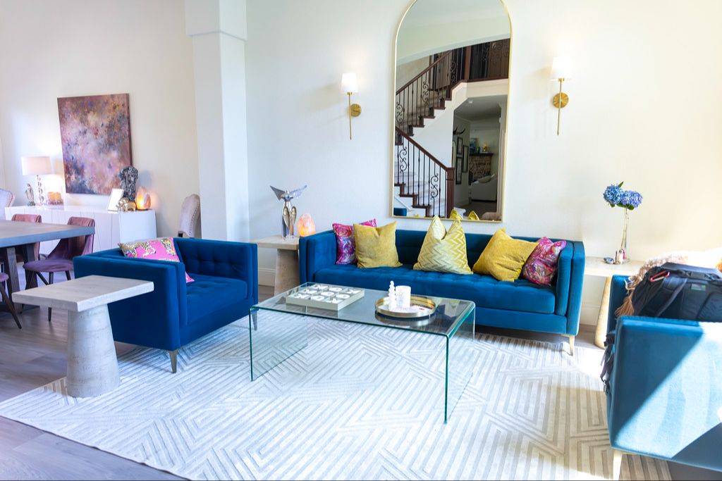 Gina's living room with blue velvet sofas, an arched mirror and gold accents