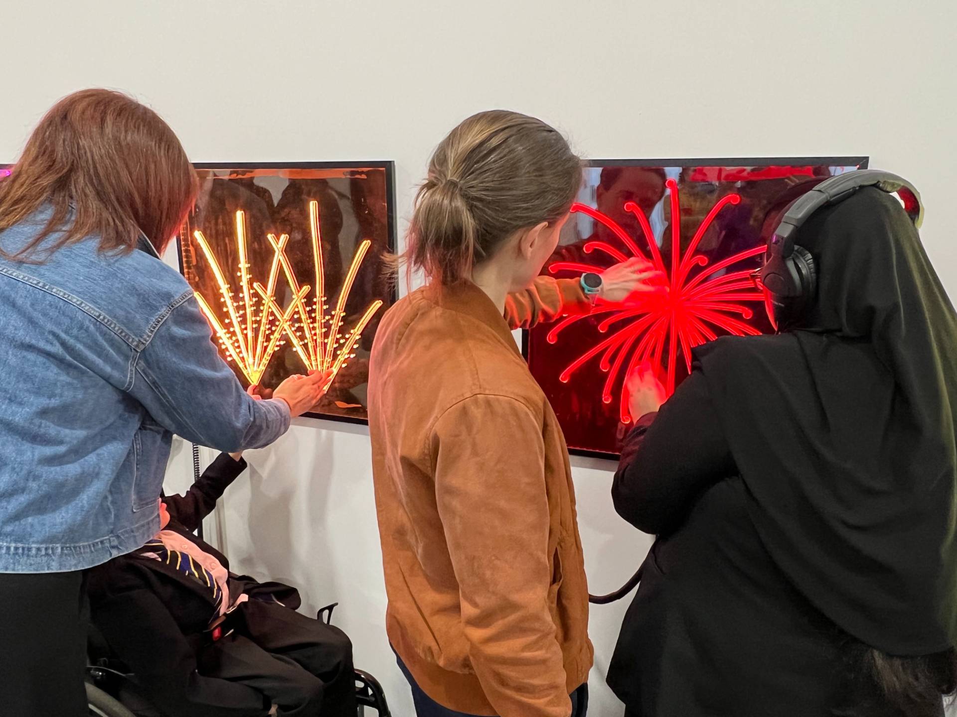 People at an art exhibition touch lit up tactile panels of fireworks