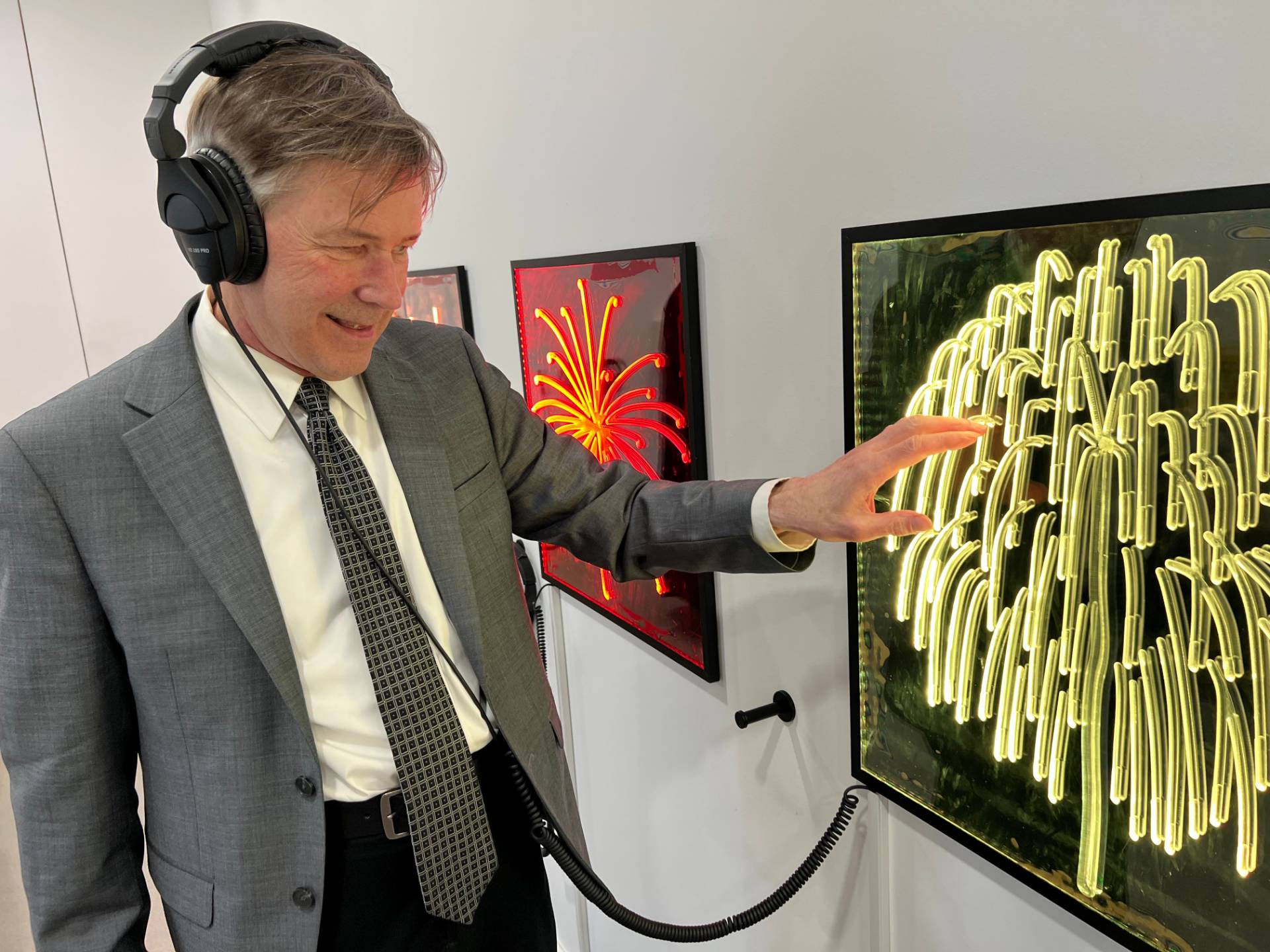 Artist Collin van Uchelen listens to an audio description of a lighted panel and traces his finger on the grooves depicting a fireworks effect