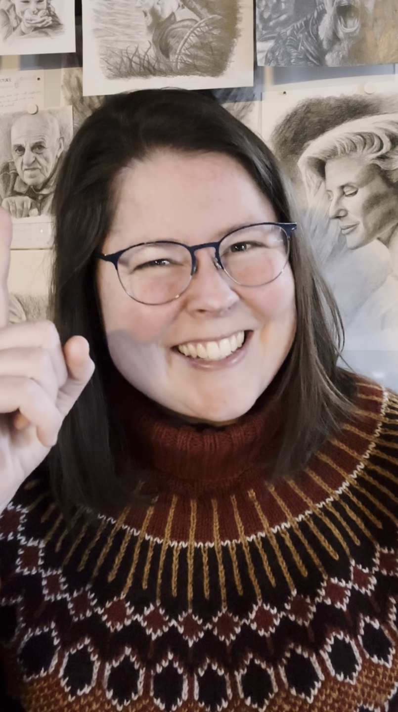 Stine smiling in front of her portrait drawings