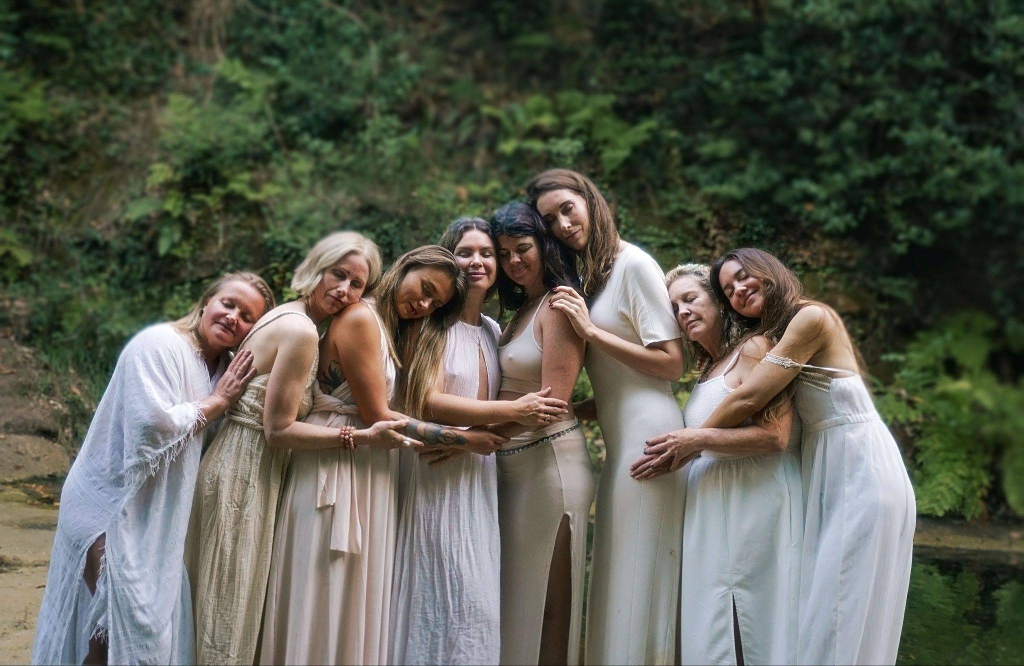 Women sharing a warm group embrace outdoors at a previous retreat 
