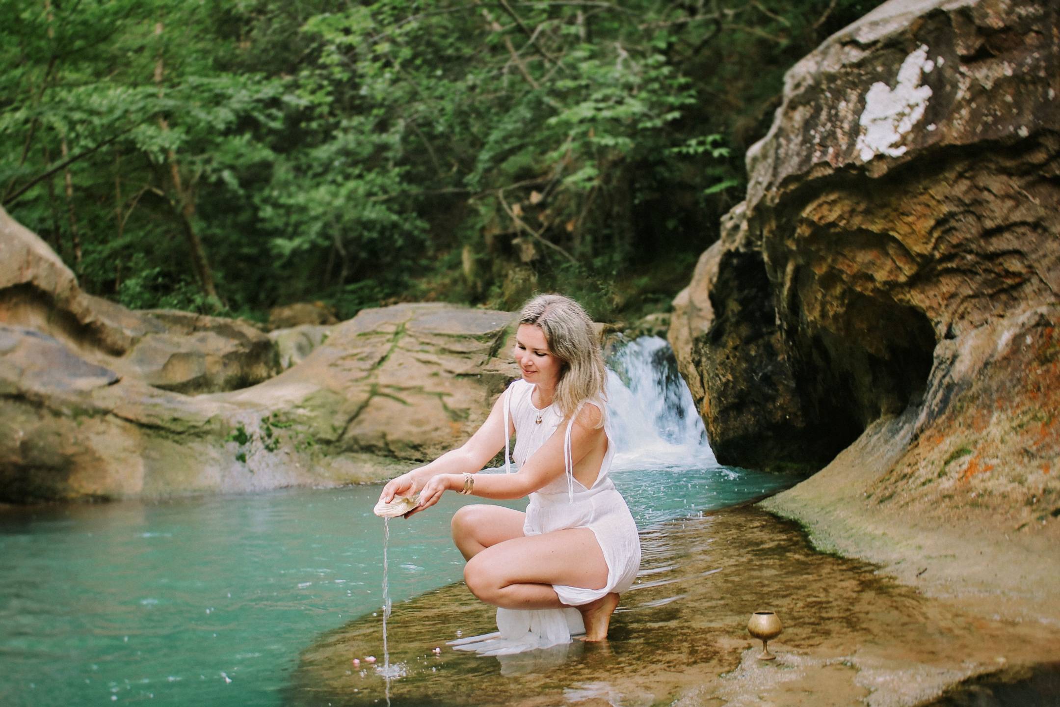 Natalia beside turquoise water and a waterfall during a previous retreat 