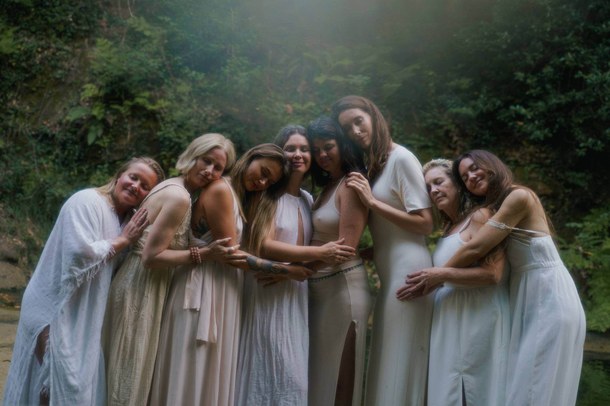 Women embracing together in a softly hazed forest during Natalia’s retreat in Southern France