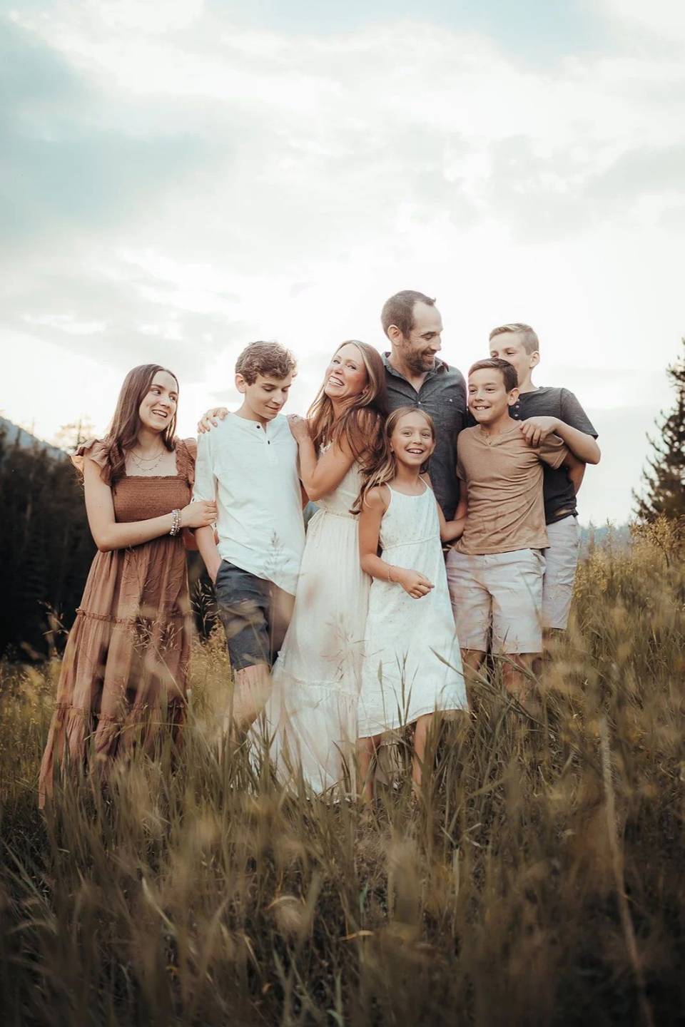 A big family standing close together in a golden meadow, photographed by Nina Turek