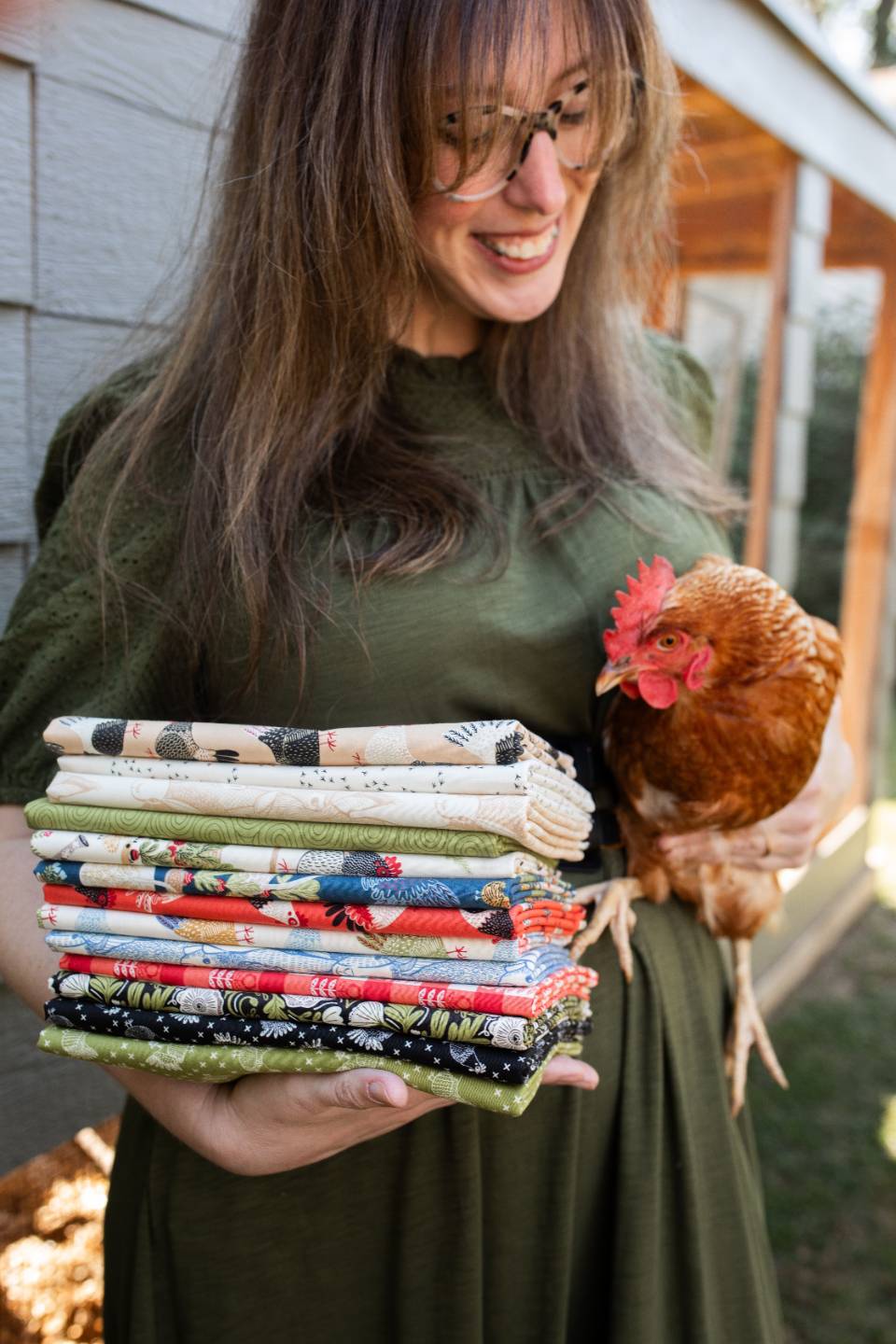 Stacie Bloomfield holding a stack of her fabric collections