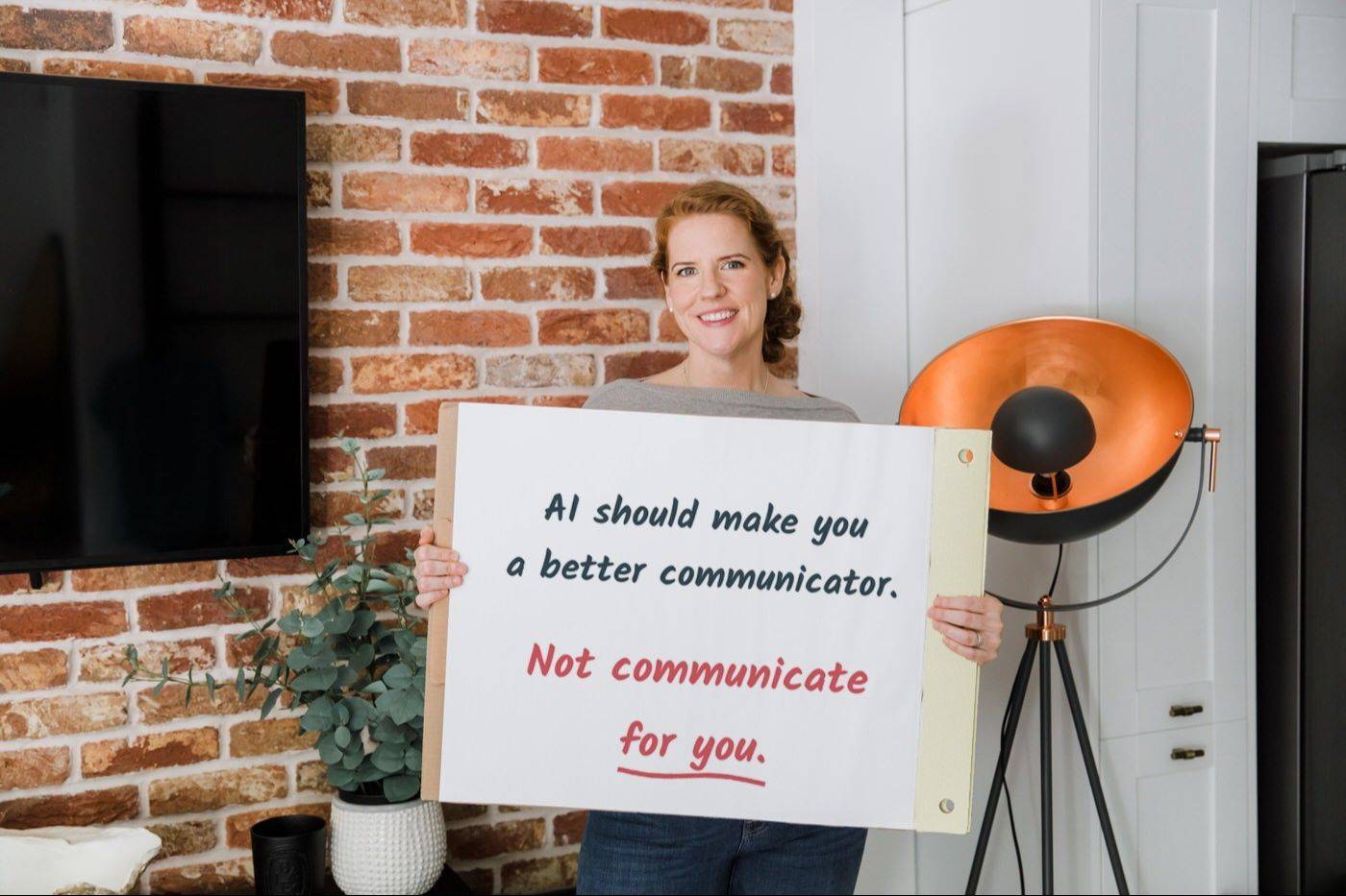 Rebecca Jabbar holding a flipchart that reads: AI should make you a better communicator. Not communicate for you.