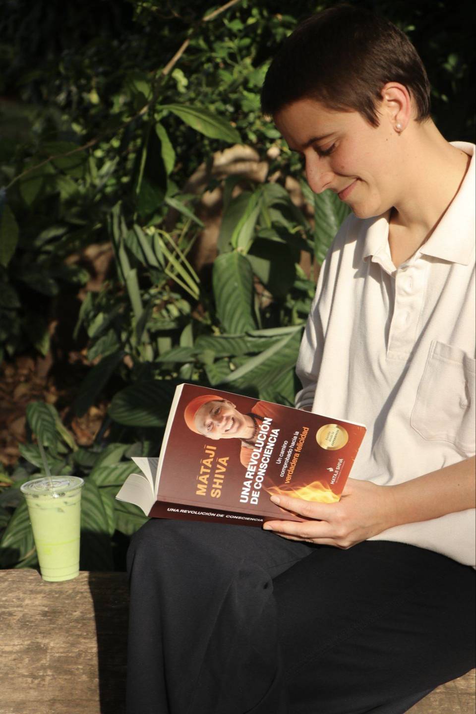 Una persona lee el libro sentada entre plantas