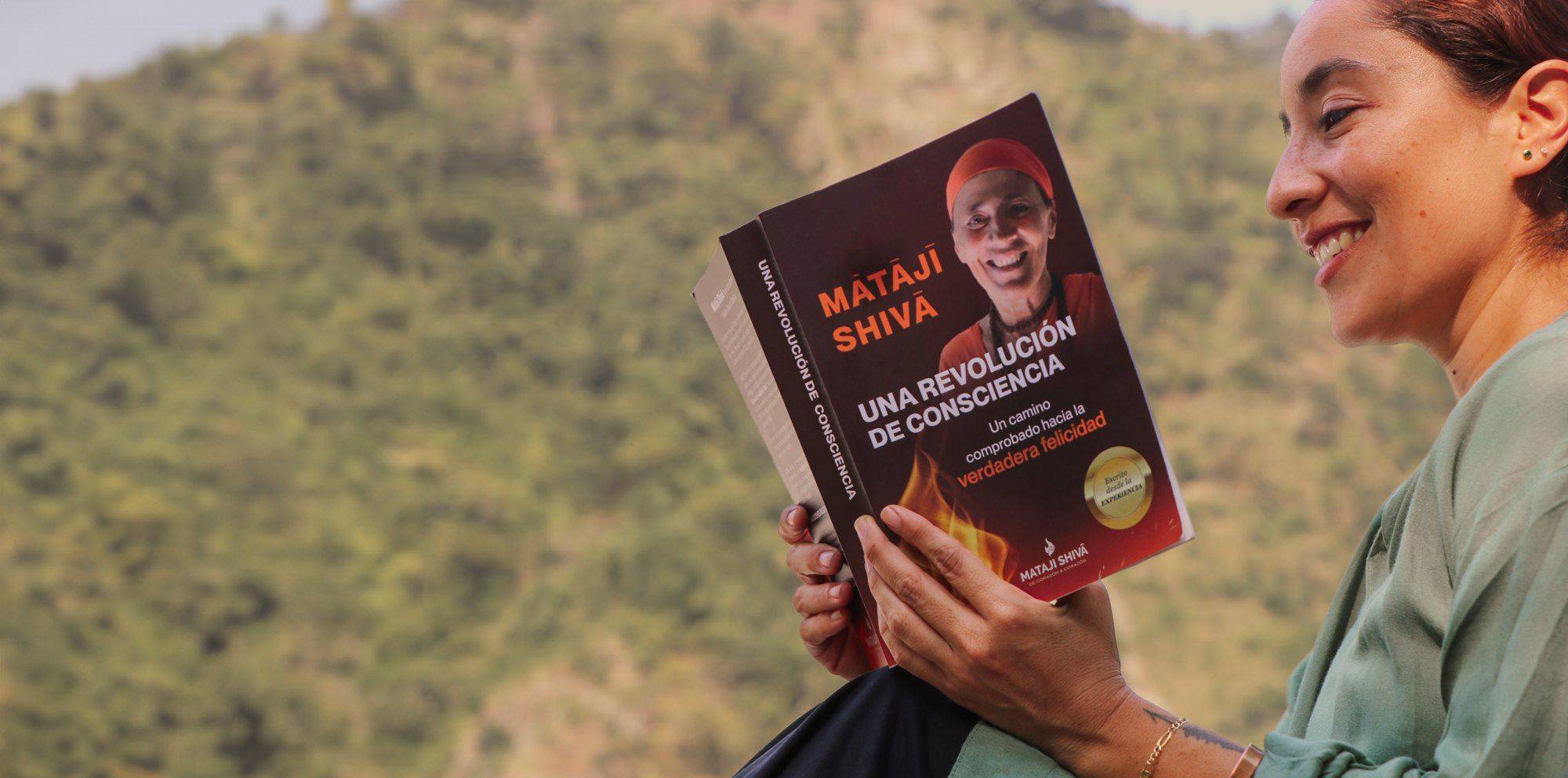 Una lectora sonríe mientras sostiene el libro de Mataji Shivā