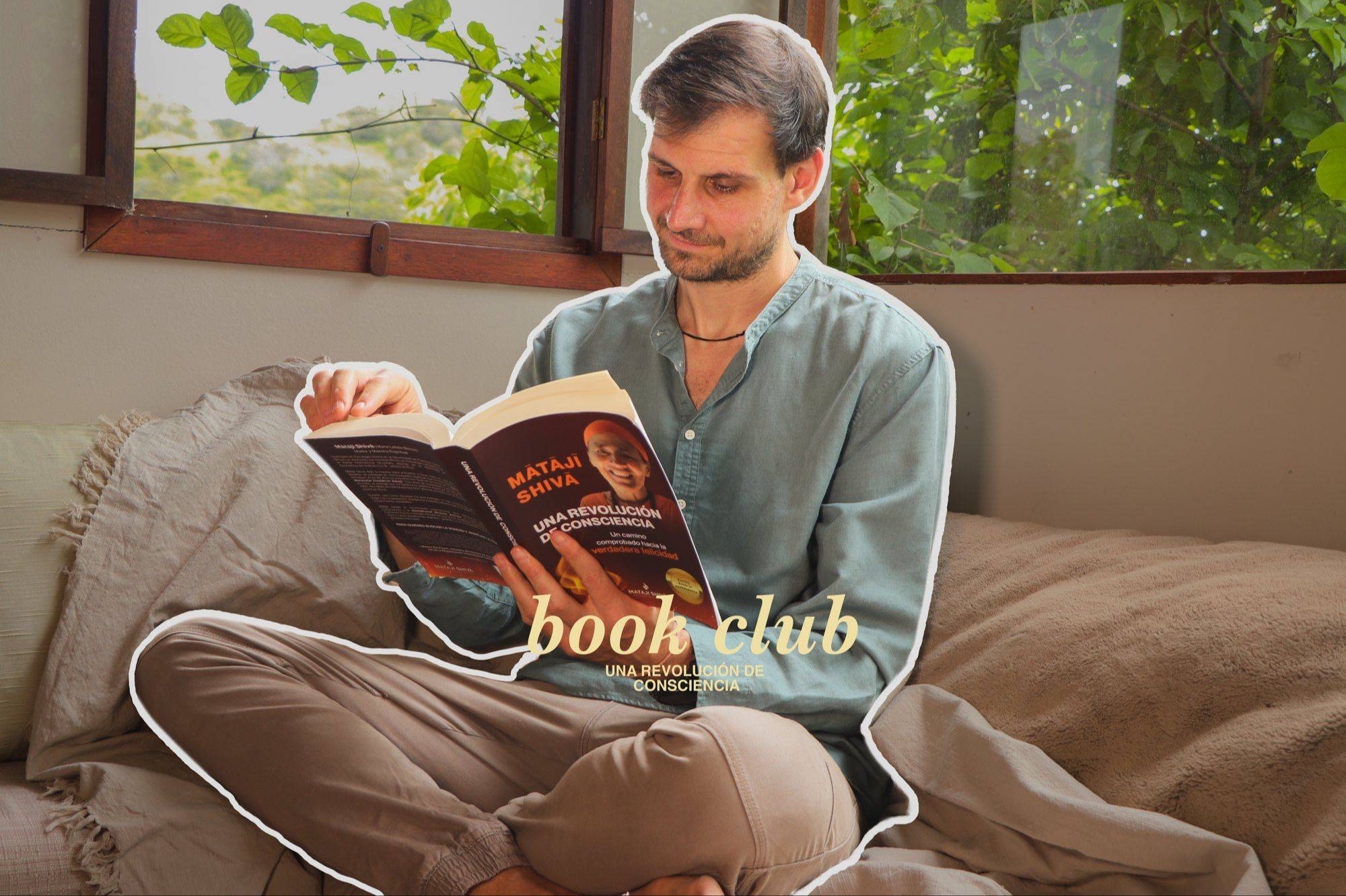 Un hombre lee el libro en un sofá junto a una ventana