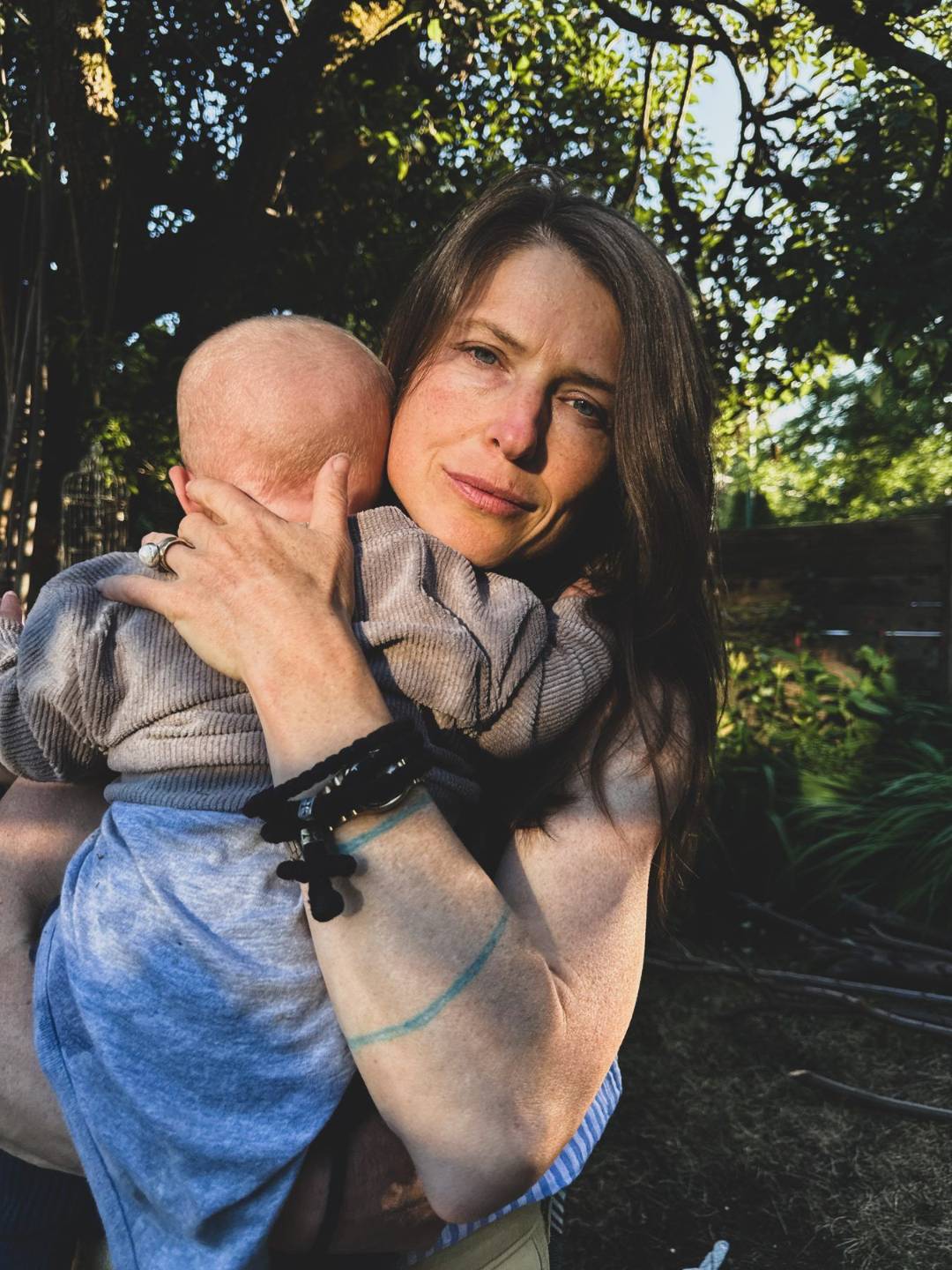 Yolande holding her baby close, prayer rope on her wrist