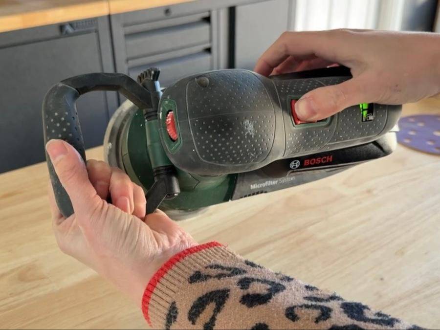 An orbital sander in her hands