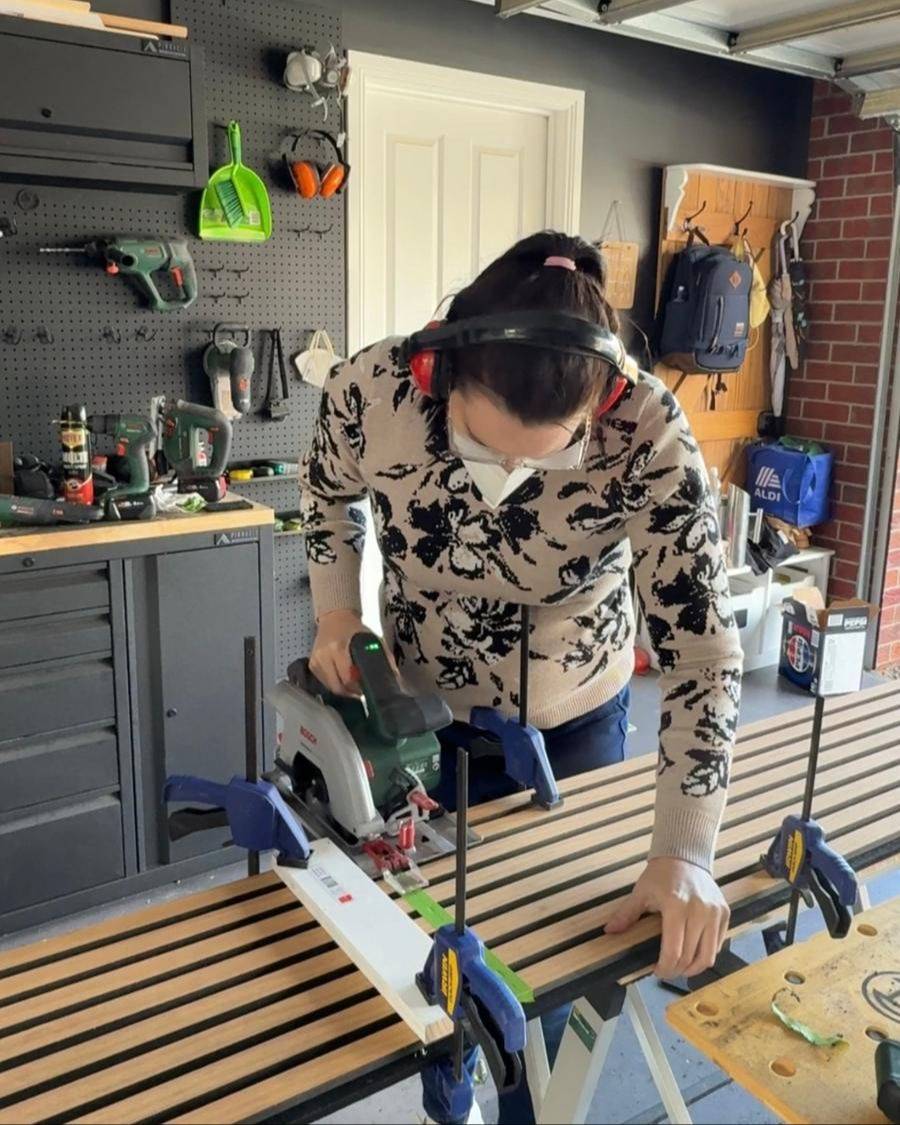 Jade cutting a slat panel with a circular saw in her garage workshop