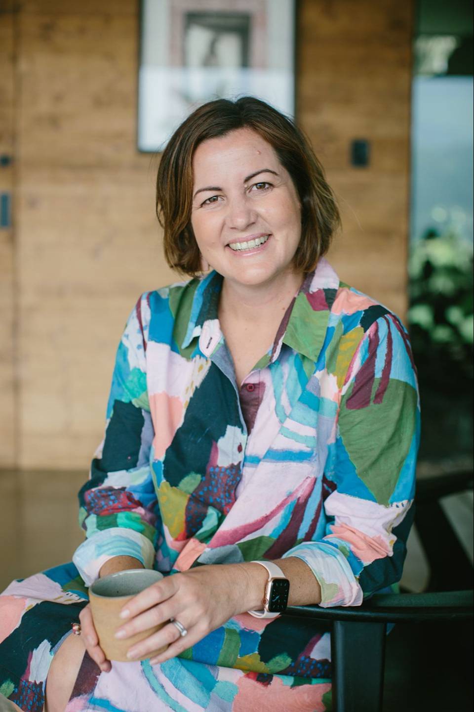 Stacey Hughes smiling and holding a coffee cup