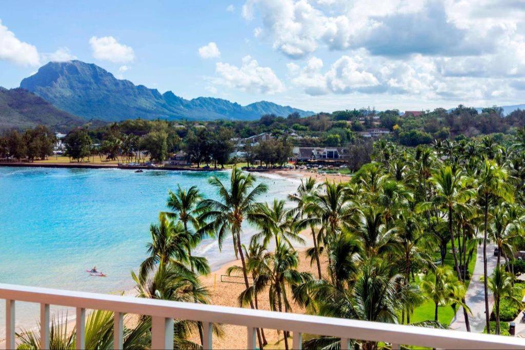View across Kalapaki Bay with palms, sandy beach and green Kauaʻi mountains