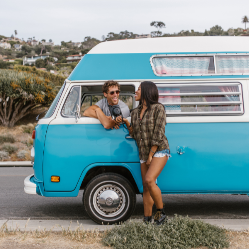A couple laughing beside a vintage blue van