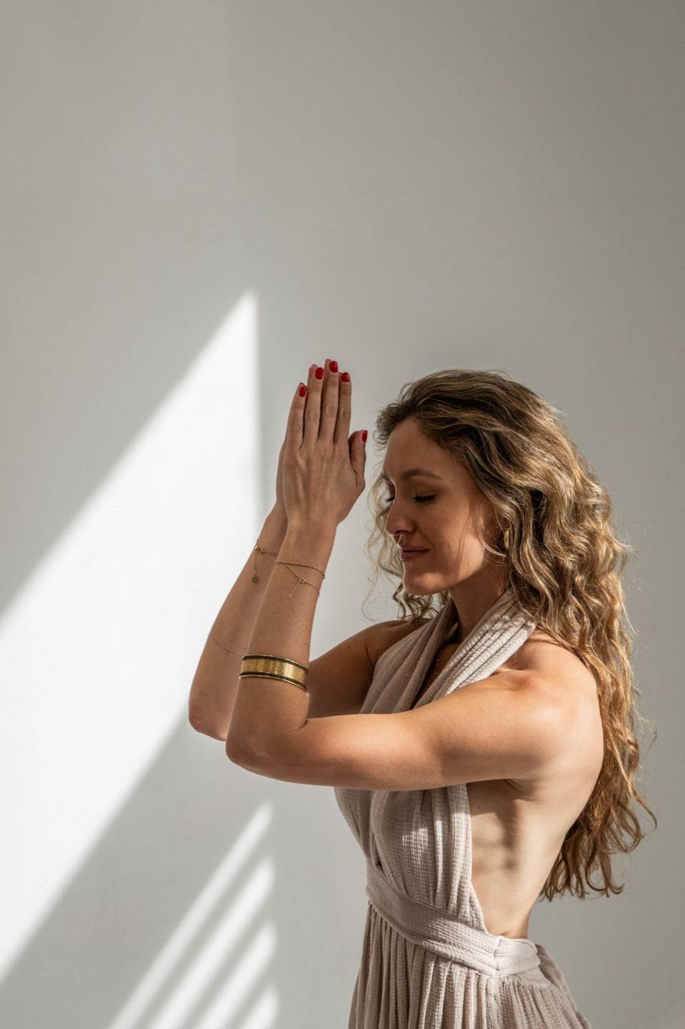Natasha with her hands in prayer, eyes closed, in soft sunlight