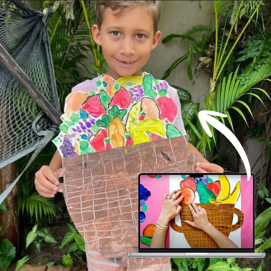 A little artist holding their finished fruit basket artwork