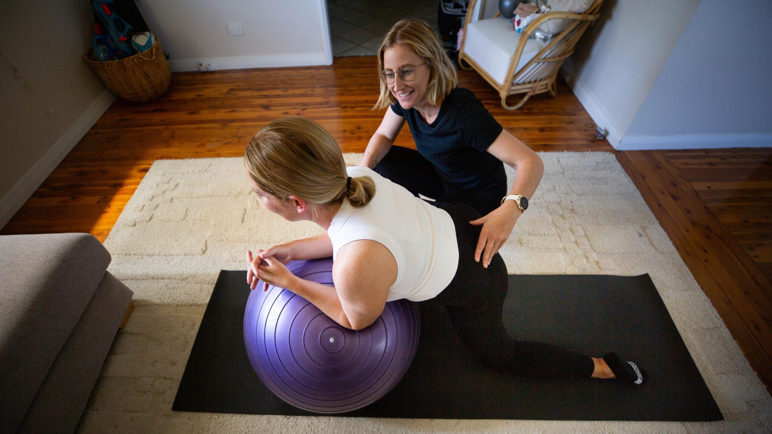 Physio supporting a pregnant woman with a fitball exercise