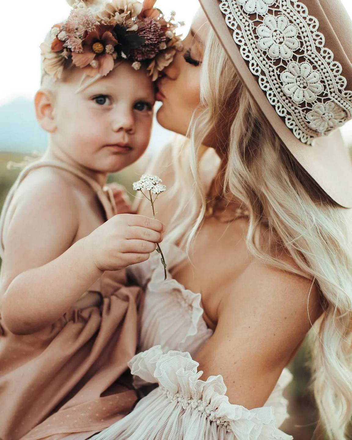 Toddler in a flower crown leaning into her mama for a kiss