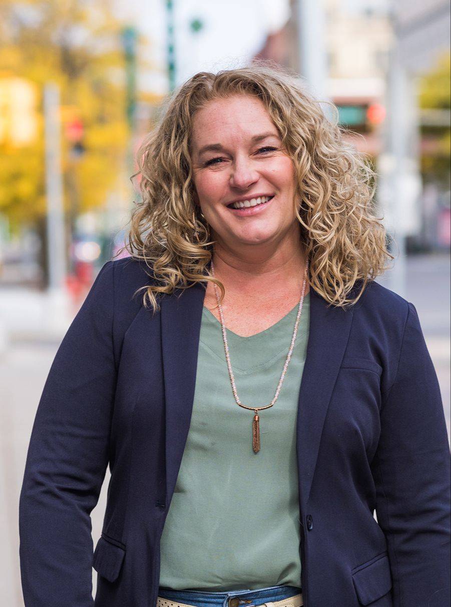 Jen Liddy, smiling at the camera, arms crossed