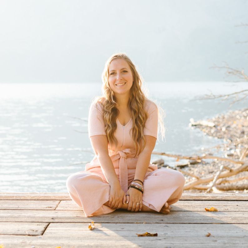 Crystal the Parenting Coach in a pink jumper sitting in front of a lake