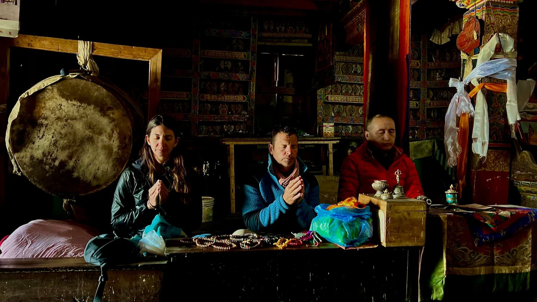 Dr. Miles Neale and Geshe Tenzin Zopa in prayer with a fellow pilgrim inside a Buddhist temple