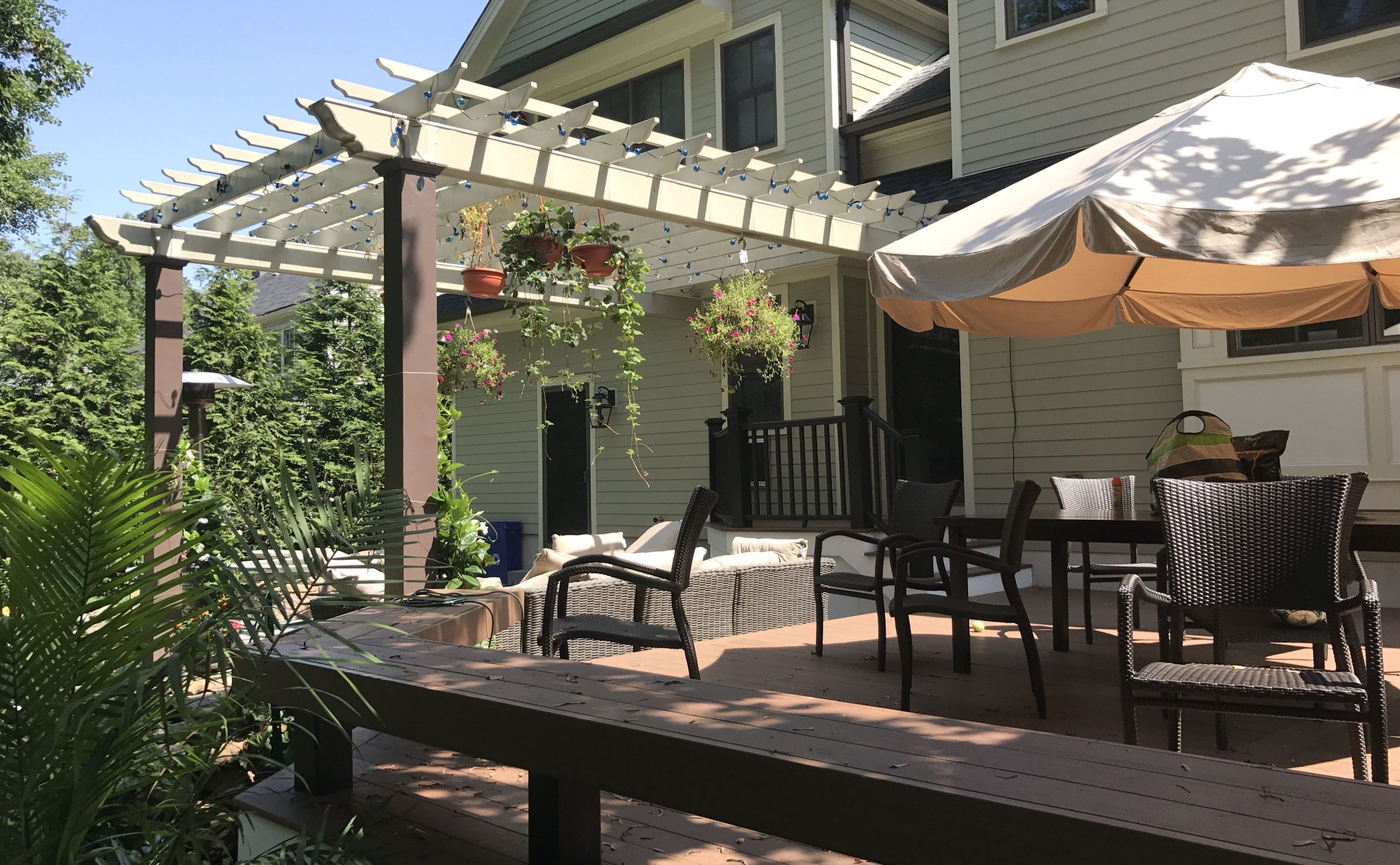 Attached Pergola with tan upper elements and brown square columns.