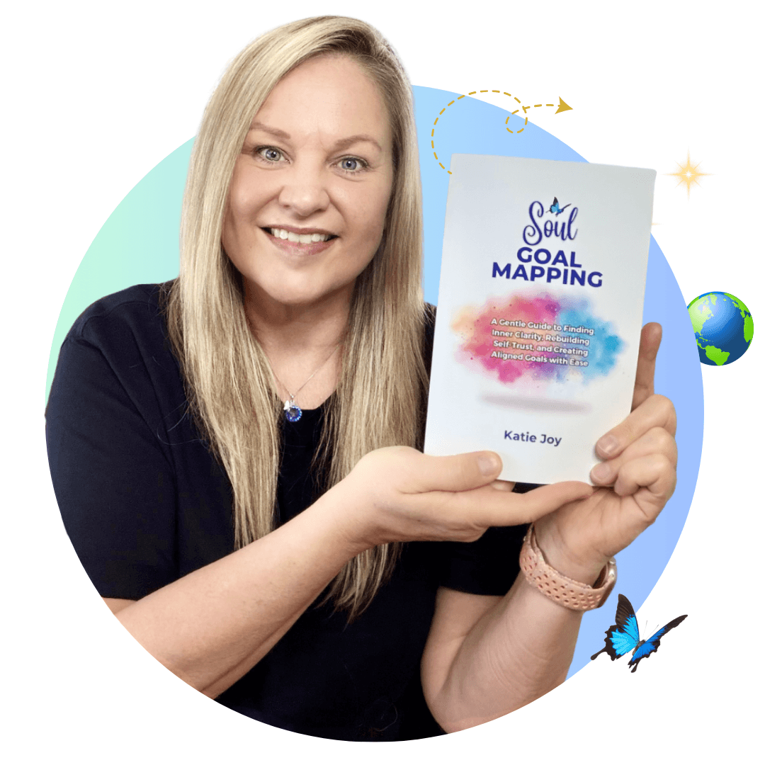 Katie Joy, author of Soul Goal Mapping™ and founder of The Global Butterfly, holding her book while representing identity recalibration, emotional healing, nervous system safety, and aligned transformation.