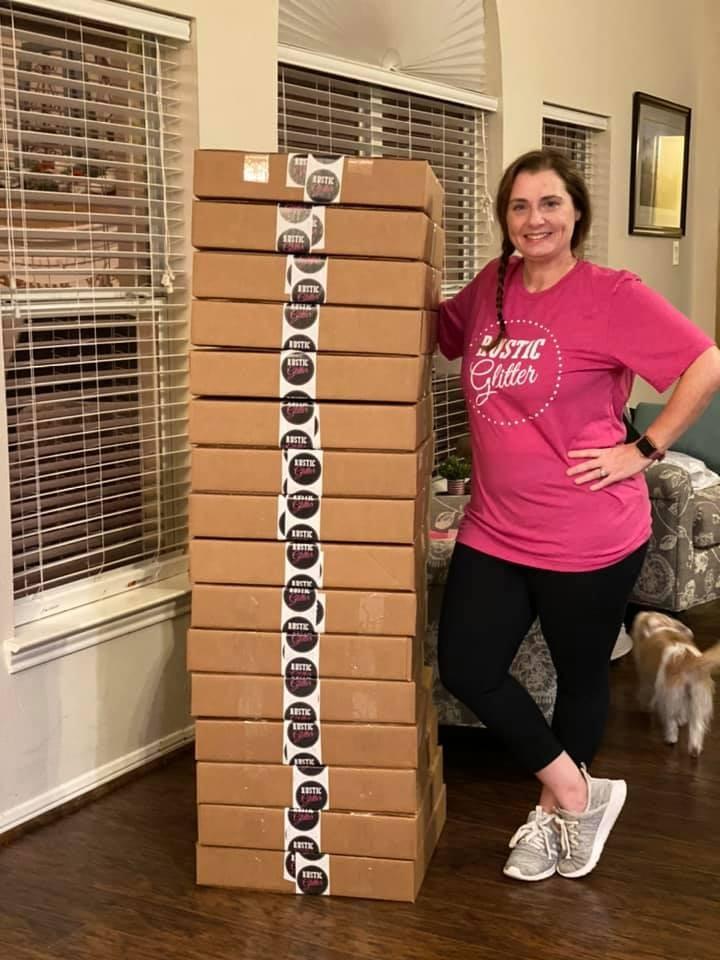 Joanne J standing next to a tall stack of brown subscription boxes