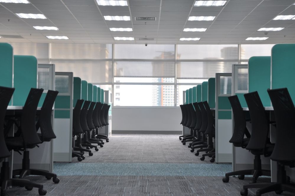 green cubicles with row of black office chairs